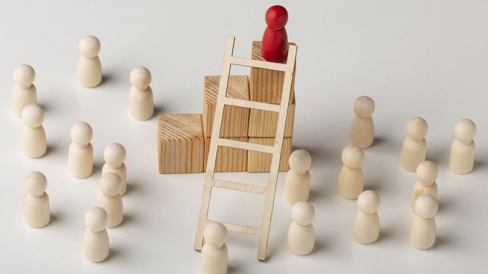 Rotes Männchen auf einer Leiter. Weiße Männchen stehen drum herum.